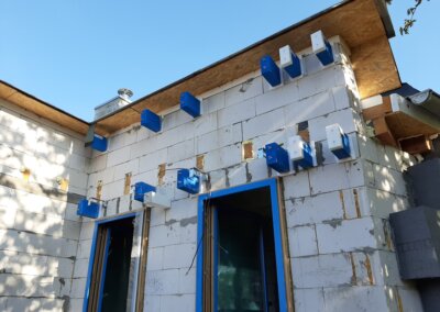 hrubá stavba domu, modré montážní bloky nad okny