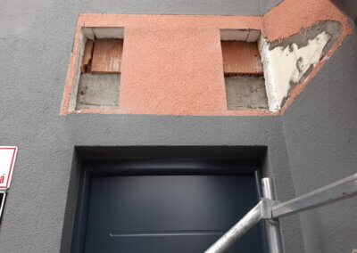 izolační vrstva fasády s velkými dírami nad vchodovými dveřmi